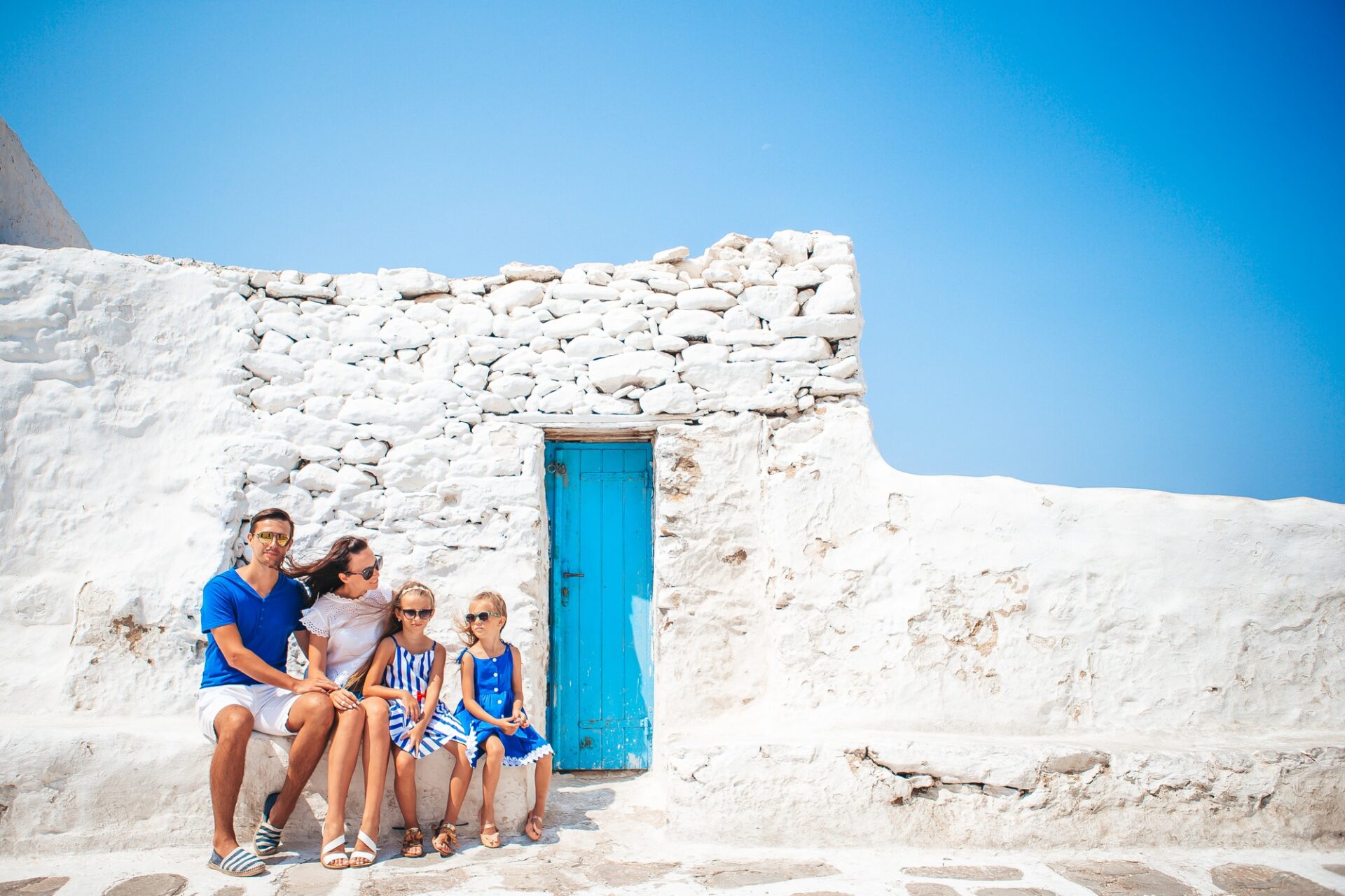 Parents and kids at street of typical greek traditional village on Mykonos Island, in Greece, Greece Financially Independent Person Visa,